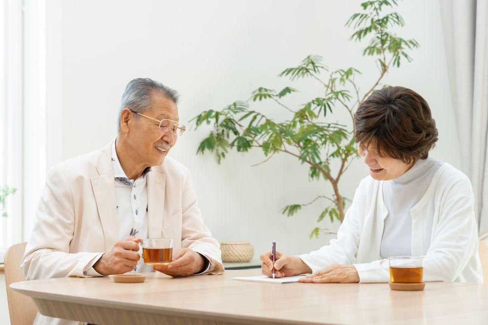 お茶を飲みながらメモをする老夫婦