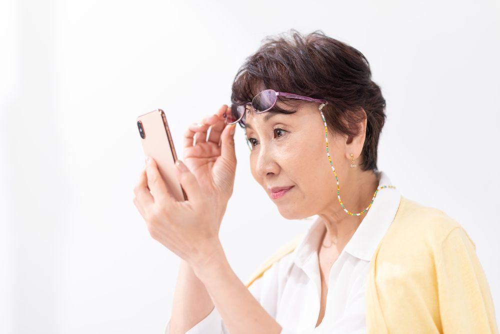 老眼を外してスマホを見るおばあさん