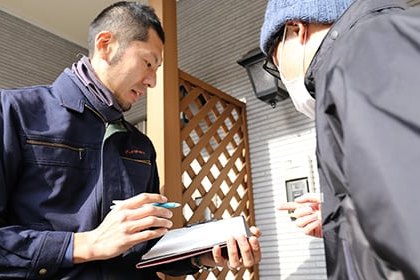 ご自宅の玄関先でお伺いの日時と作業内容を確認するスタッフ