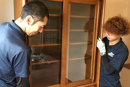 食器棚の中をライトで照らしながら2名で査定するスタッフ