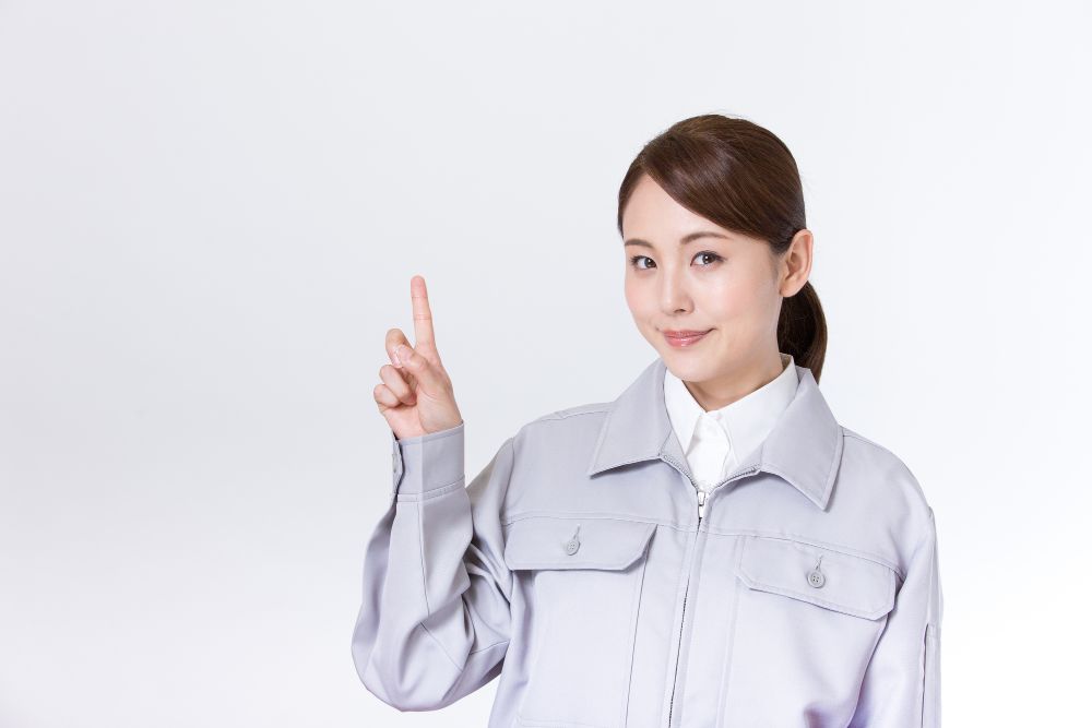 作業着の女性が人差し指を立てている