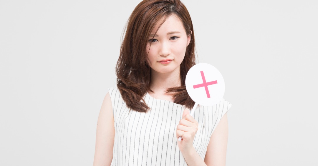 女性が×の標識を持つ